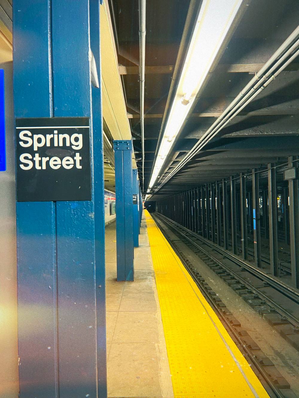 empty nyc subway platform with a sign postage “spring street”
