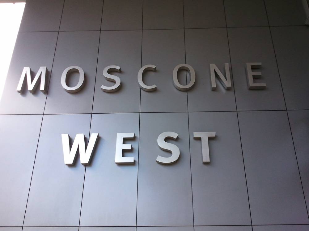 Metal letters spelling 'MOSCONE WEST' are mounted on a tiled wall.