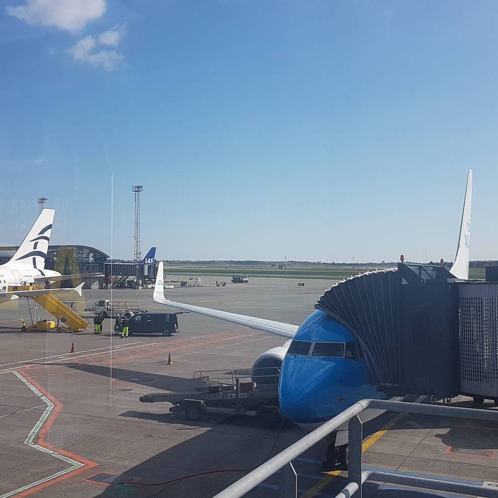 An airplane parked at an airport gate with ground service vehicles nearby.