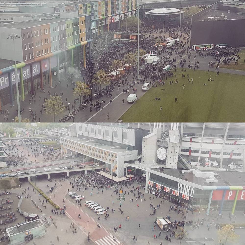 Aerial view of a crowded city square and shopping center with a large screen and stage.
