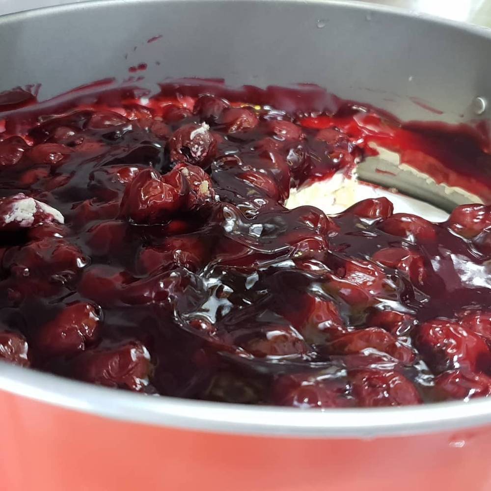 A pot of cooked cherries simmering with a scoop of ice cream.
