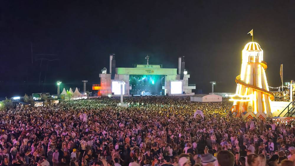 A nighttime festival crowd faces a brightly lit stage.