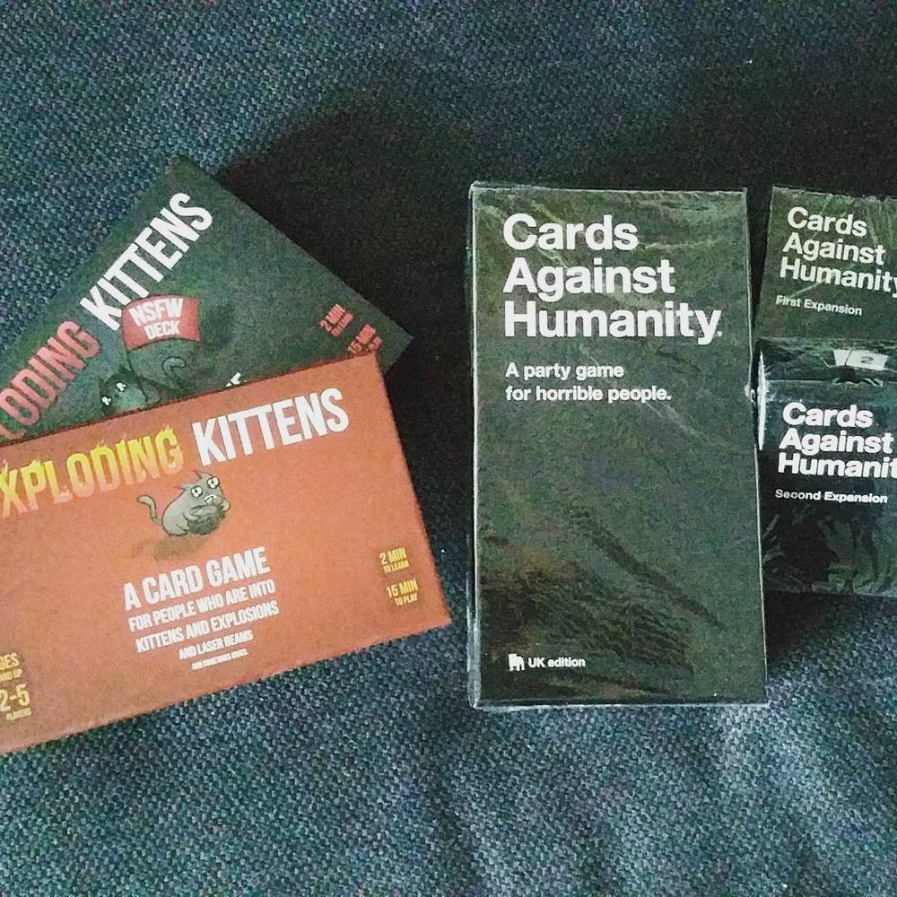 Boxes of the card games Exploding Kittens and Cards Against Humanity on a table.
