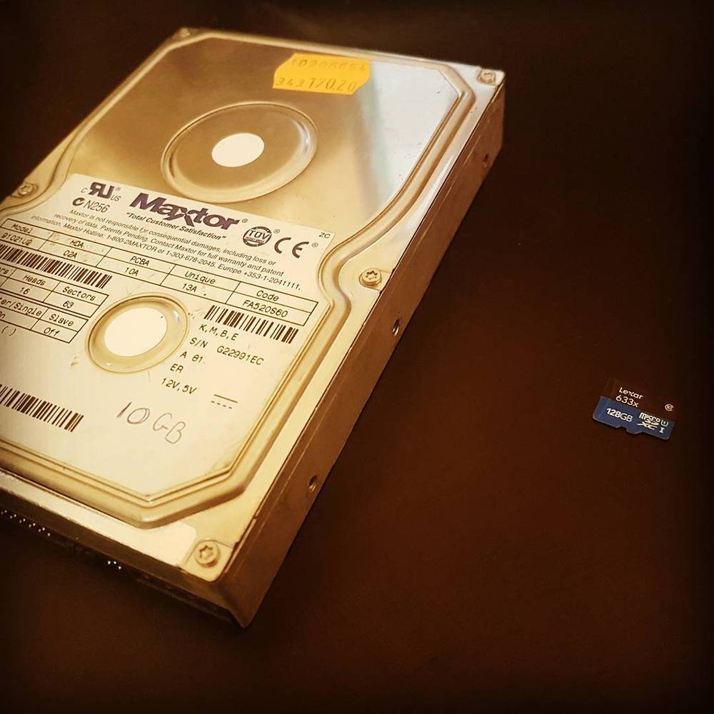An old Maxtor hard drive next to a tiny memory card, showing the size difference.