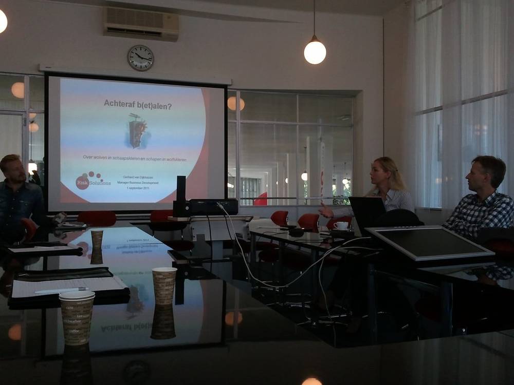 A presenter addresses a small group beside a slide about paying afterward.
