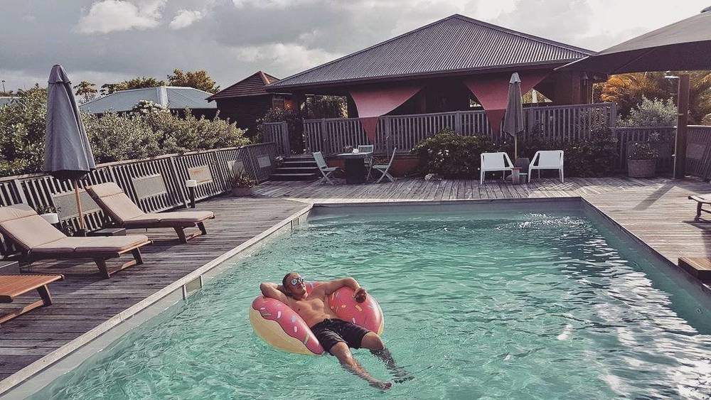 A pool deck with loungers and a person relaxing on an inflatable donut float.