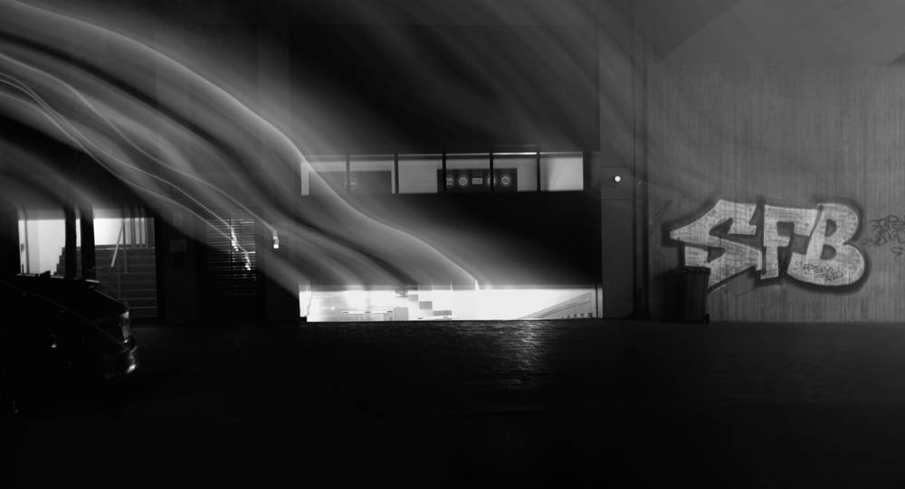 Nighttime b/w shot of a closing roller door with the bright light from inside escaping, blurred by camera movement