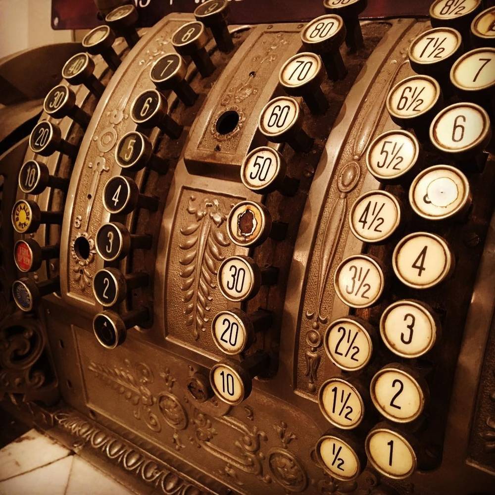 A close-up of the ornate keys and mechanism of an antique brass cash register.