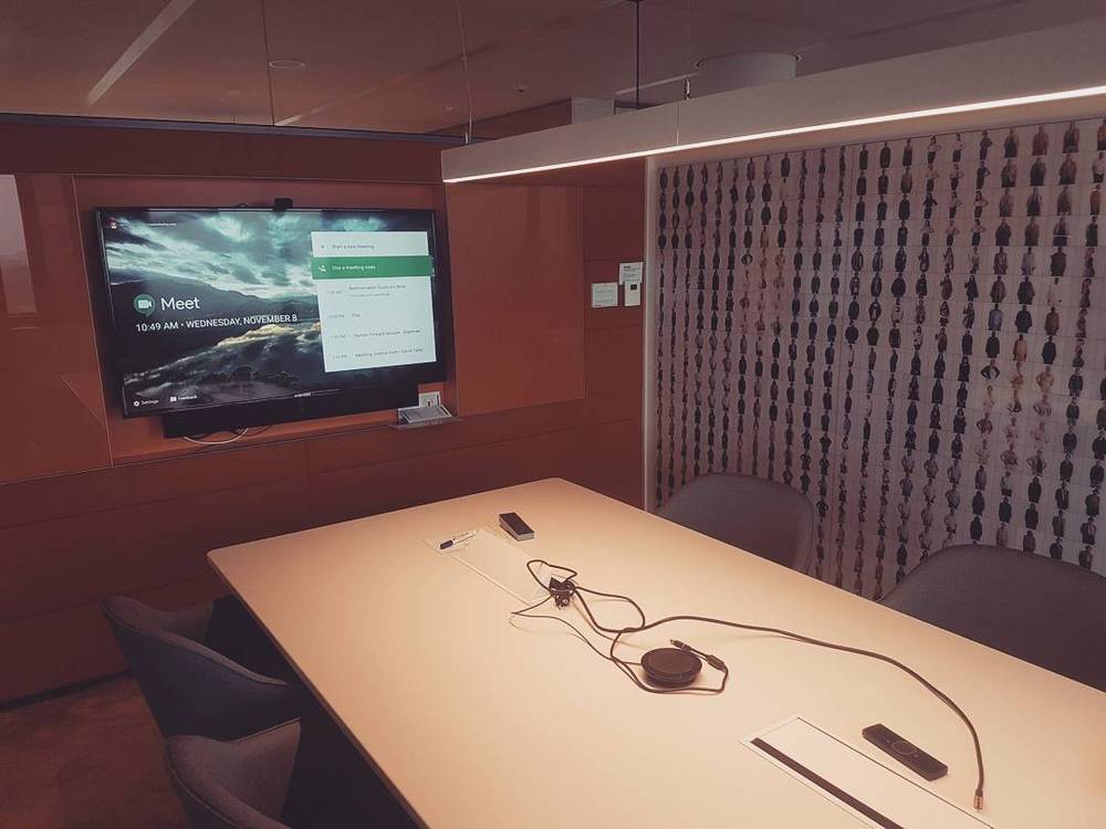 An empty meeting room with a video call ready on the wall-mounted screen.