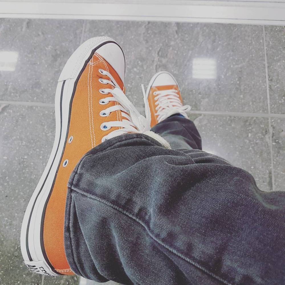 Close-up of orange sneakers on the floor of an airport.