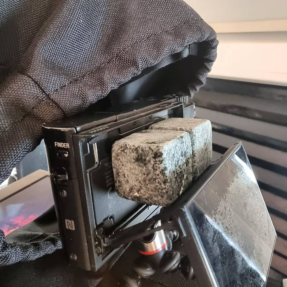 Close-up of a vintage camera's viewfinder and hood, backlit by a sunset sky.