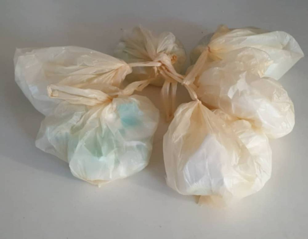 Several tied plastic bags, used nappies, sit on a countertop.