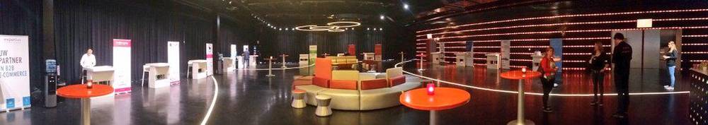 An empty conference exhibition hall set up with lounge seating and round tables.