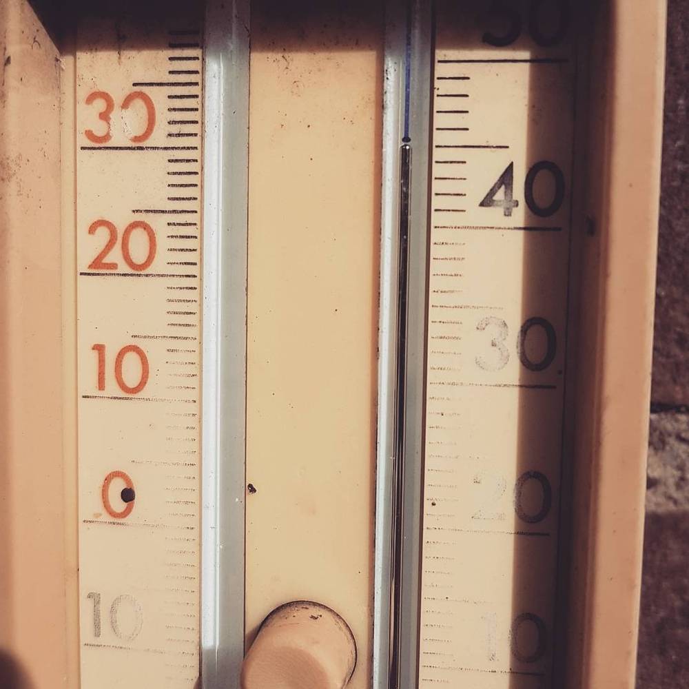 An outdoor thermometer mounted on a wall, reading close to 45 degrees Celsius.