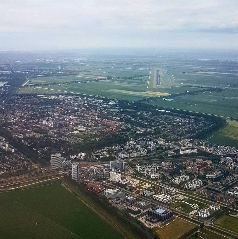 Aerial view of farmland and a town near an airport runway, seen from a plane.