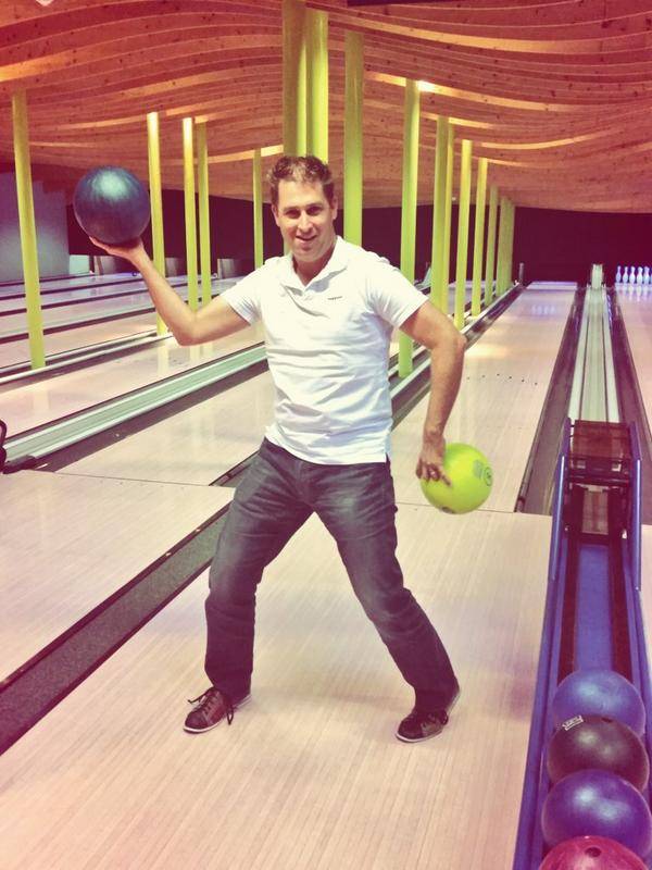 A man winds up to throw a bowling ball down the lane.