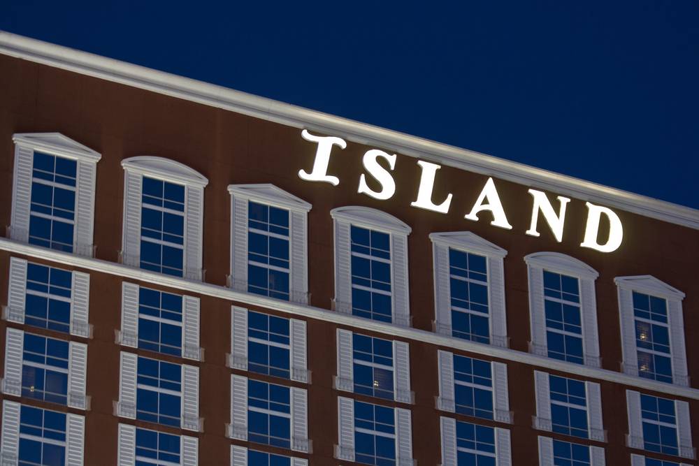 The illuminated 'ISLAND' sign glows on the side of a Las Vegas hotel tower at night.