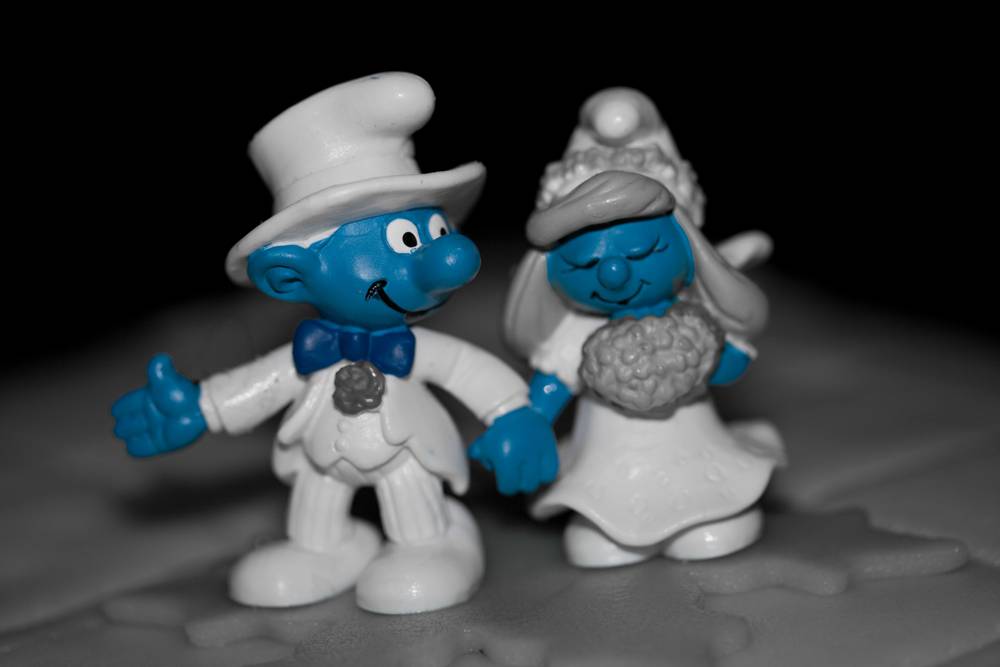 A black-and-white smurf-figure bride and groom stand as a wedding cake topper.