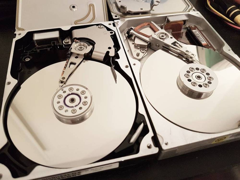 Two disassembled hard drives with their internal disks and read arms exposed.