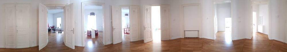 A panoramic view of an empty apartment with open doors and wooden floors, in Leipzig.