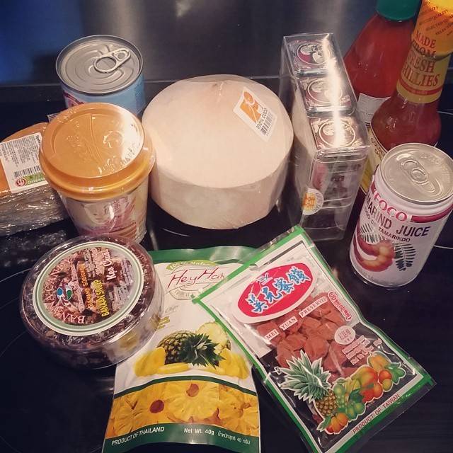 An assortment of Asian grocery items including canned goods, packaged snacks and juice on a table.