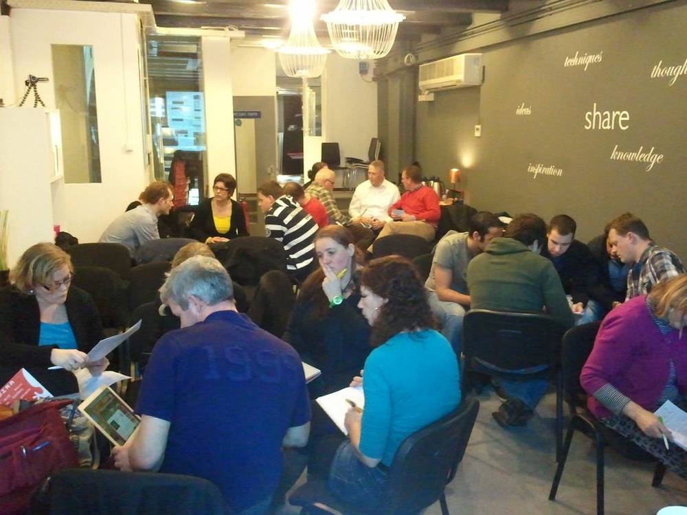 A larger group of workshop attendees discusses in a circle in the same venue.