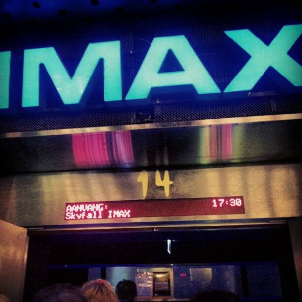 An illuminated IMAX cinema sign above a box office showing a listing for 'Skyfall IMAX' at 17:30.