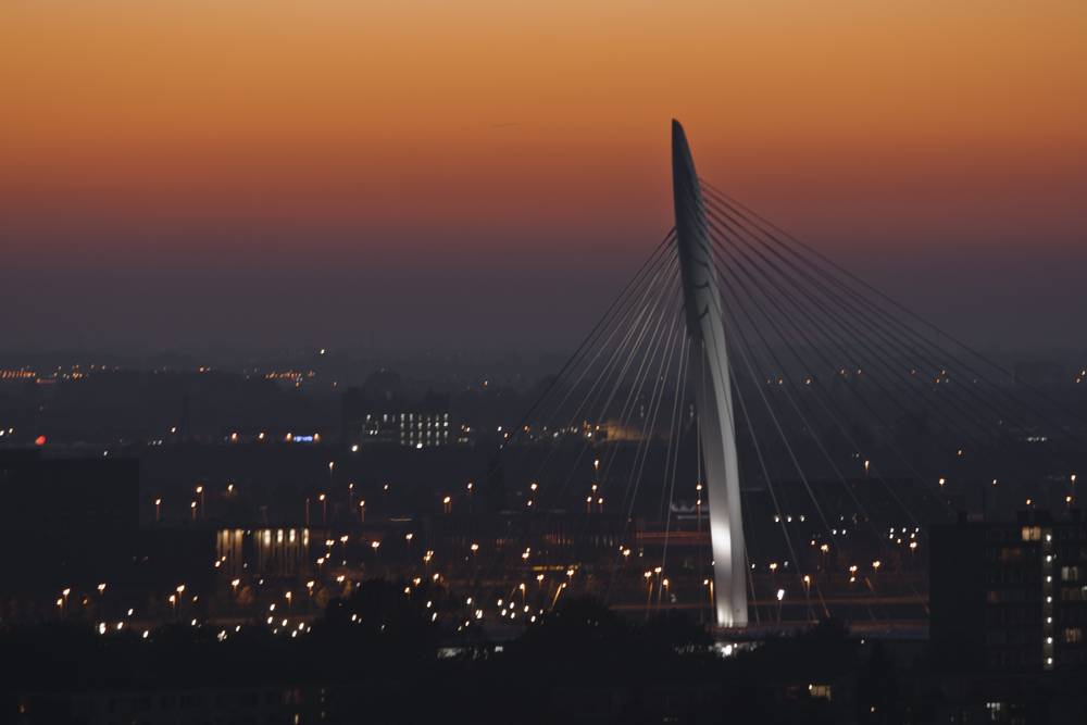 The same bridge glows warmly at dusk above the city lights of Utrecht.