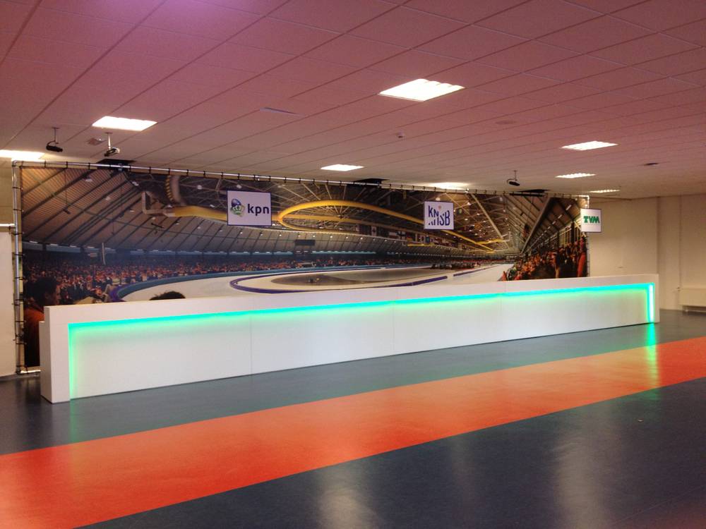 The interior of the Thialf ice skating stadium with sponsor banners around the rink.