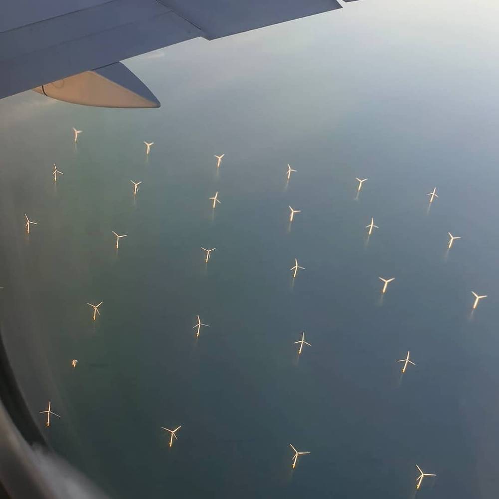 View from an airplane window of an offshore wind farm at sea.