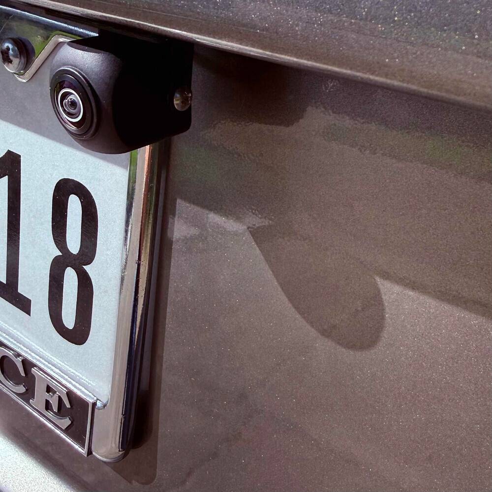 A close-up view of a car's rear license plate with a mounted backup camera above the plate.