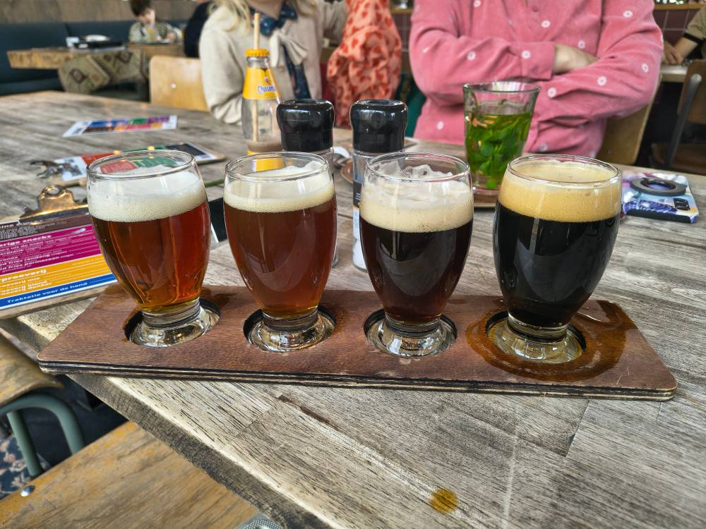 4 small glasses of beer on a table. Ranging from red brown to black. 