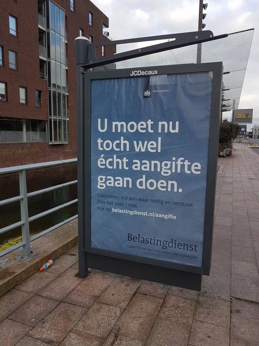 A street billboard advertisement for the Dutch tax office reads "You really should file your taxes now."