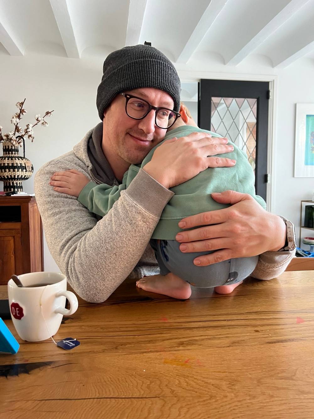 A man lies on a table hugging a child close to him.